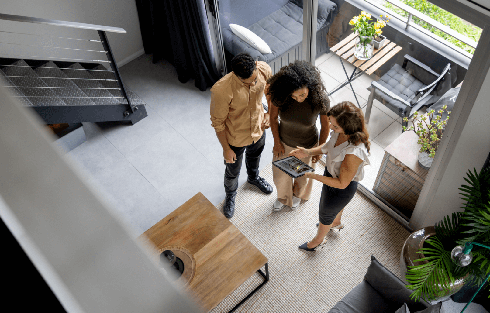 a couple and a realtor looking at images on an iPad while standing inside a modern living room