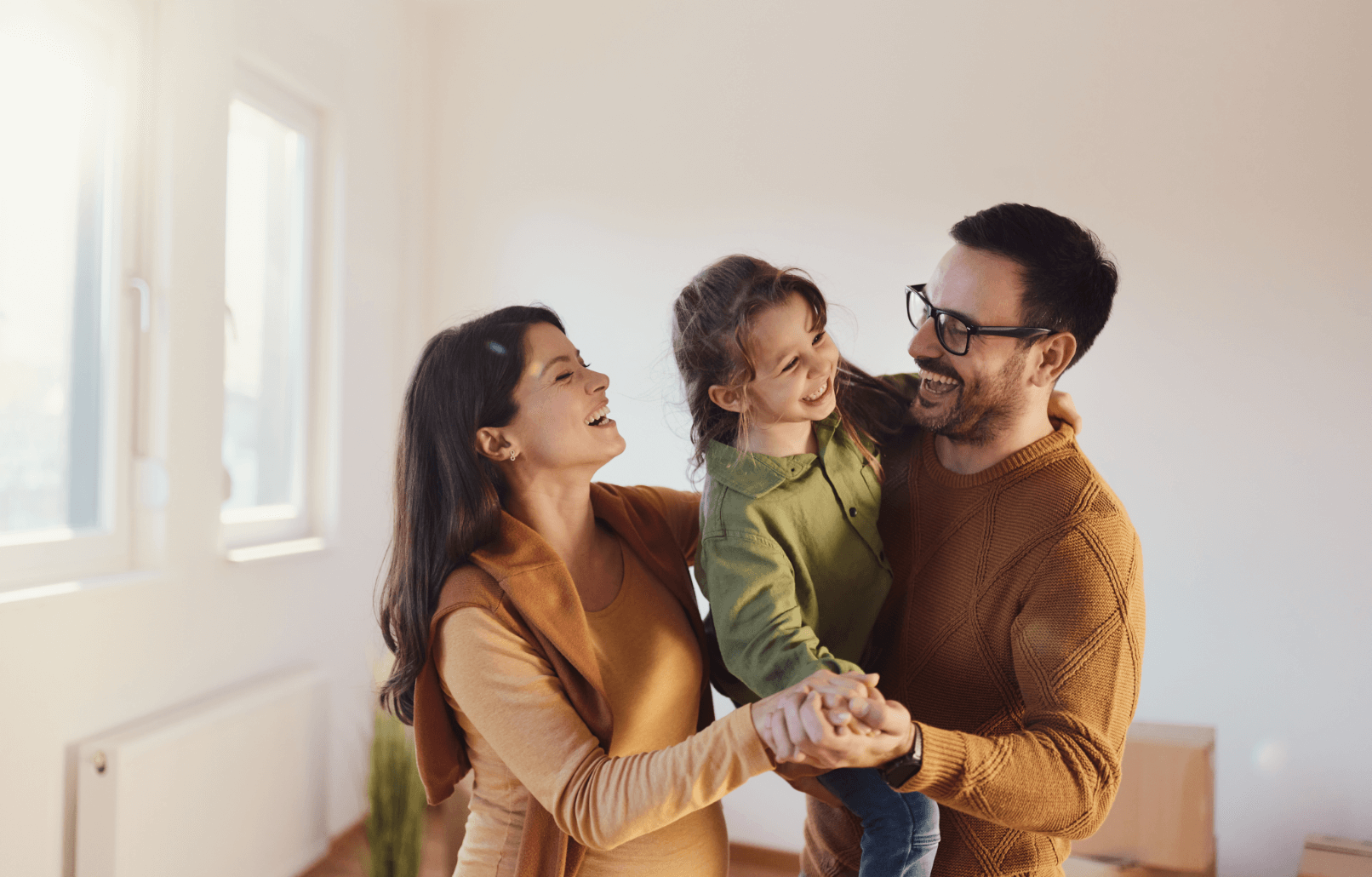 a family of three dancing together in a living room